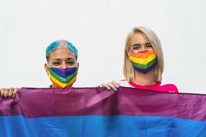 Happy gay couple wearing face mask celebrating gay pride event during corona virus pandemic photo