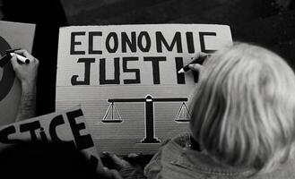 Senior activist preparing protest banners against financial crisis - Economic justice activism concept - Black and white editing photo