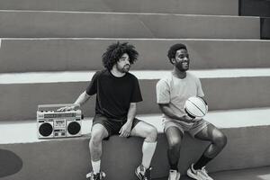 Happy African American men listening music inside basketball court with vintage boombox stereo - Urban street people lifestyle - Black and white editing photo