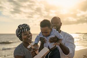 contento africano familia teniendo divertido en el playa durante verano vacaciones - padres amor y unidad concepto foto