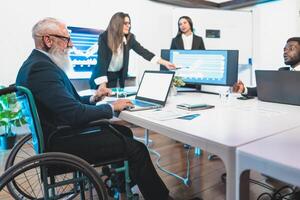 a business man in a wheelchair is sitting at a table with other people photo