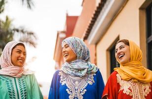 contento musulmán mujer caminando en el ciudad centrar - árabe joven muchachas teniendo divertido gasto hora y riendo juntos al aire libre - concepto de gente, cultura y religión foto