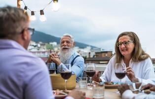 Happy senior friends having fun dining together on house patio - Elderly lifestyle people and food concept photo