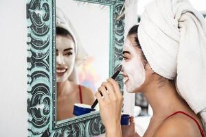 Young woman applying daily facial cream - Happy girl having skin care spa day portrait - Healthy beauty clean treatment and cosmetology products concept photo