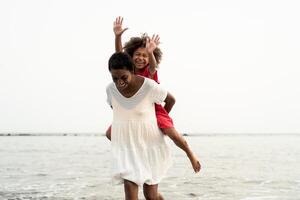 Happy African family on the beach during summer holidays - Afro American people having fun on vacation time - Parents love and travel lifestyle concept photo