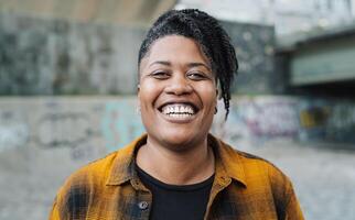 contento africano mujer sonriente en frente de un cámara en el ciudad foto