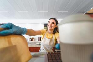 bar propietario trabajando solamente con tomar lejos pedidos durante corona virus brote - joven mujer trabajador vistiendo quirúrgico guantes dando eliminar comida a clientes - cuidado de la salud y comida bebida concepto foto