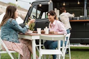 Happy mature women having fun eating in a street food truck outdoor photo