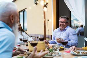 Happy senior friends having fun dining together on house patio - Food and elderly people lifestyle concept photo