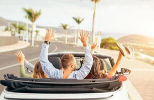 contento amigos teniendo divertido en convertible coche a puesta de sol en vacaciones - joven personas haciendo fiesta y bailando en un cabrio auto durante su la carretera viaje - amistad, viajar, juventud estilo de vida concepto foto