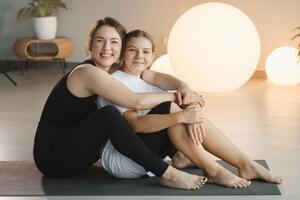 portrait of a mother and daughter of a teenager in sports clothes hugging, who are together in a fitness room. the concept of family sports photo