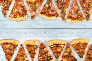 Lots of delicious triangular pizza slices on a blue wooden background photo