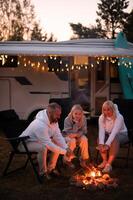 A family cooks sausages on a bonfire near their motorhome in the woods photo