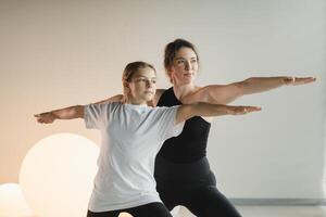 Mom and teenage daughter do gymnastics together in the fitness room. A woman and a girl train in the gym photo