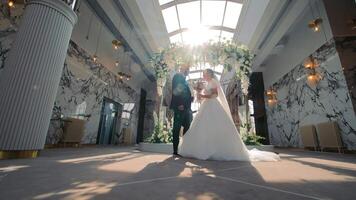 zonovergoten geloften. bruid en bruidegom onder bloemen boog, een stralend bruid en bruidegom staan onder een bloemen boog in een luxueus locatie, badend in zonlicht. video