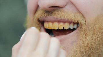 un mujer pinturas su dientes con amarillo pintar. el estilista hace arriba el actor. amarillo dientes en un hombre. video