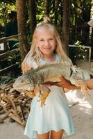 Summer portrait of a happy little girl in a zoo on the island of Mauritius with an iguana.little girl in the zoo with a crocodile in her arms photo