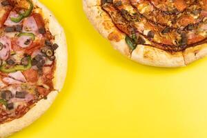 dos diferente delicioso grande pizzas en un amarillo antecedentes foto