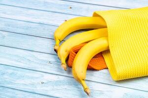 yellow bananas lying in a yellow bag on a blue wooden background photo