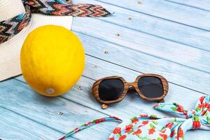 Top view of a straw white hat with glasses and a swimsuit, lying on a blue wooden background.Summer vacation concept photo