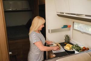 a woman cooking food in the kitchen inside a motorhome, the interior of a motorhome photo