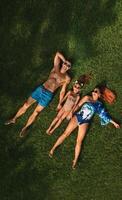 Top view of a happy family in swimsuits lying on the green grass photo