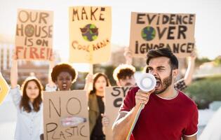 Group of activists protesting for climate change - Multiracial people fighting on road holding banners over environments disasters - Global warming concept photo