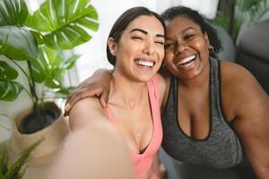 Young Latin women taking selfie with smartphone cam while doing yoga and pilates at home - Sport wellness lifestyle concept photo