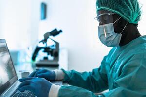 Medical worker wearing personal protective equipment using computer inside clinic during corona virus outbreak - Research and development concept photo