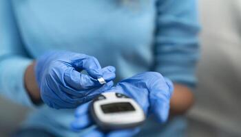 Young nurse checking glycemia test for diabetes while wearing surgical gloves - Healthcare concept - Soft focus on gloves photo