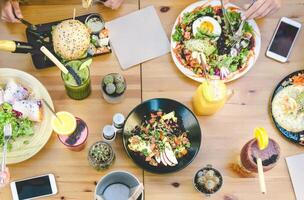 contento amigos almorzando con sano comida en bar café desayuno tardío - parte superior ver joven personas teniendo comida comiendo y Bebiendo batidos Fresco frutas en rústico restaurante - salud dieta estilo de vida concepto foto