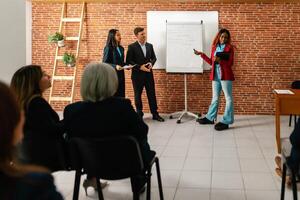 a group of people in business attire standing in front of a whiteboard photo