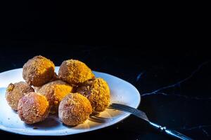 cheese balls with garlic and dill inside for a snack in a white plate on a black background photo