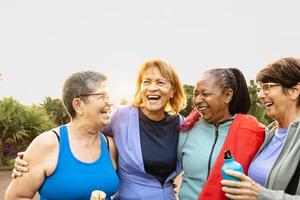 Happy multiracial senior women having fun after workout exercises in the park photo