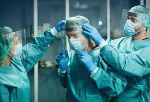 Doctors wearing ppe equipment face surgical mask and visor fighting against corona virus outbreak - Health care and medical workers concept photo