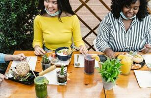 Young multiracial friends having healthy lunch in coffee brunch bar during covid19 photo