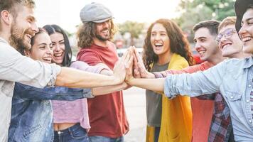 Group of diverse friends stacking hands outdoor - Happy young people having fun joining and celebrating together - Millennials, friendship, empowering, partnership and youth lifestyle concept photo