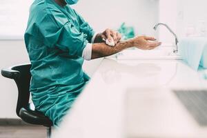 Surgeon washing hands before operating patient in hospital - Medical worker getting ready for fighting against corona virus pandemic - Health care and hygiene concept photo