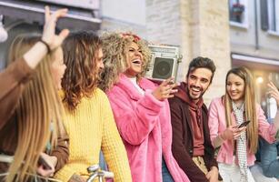 Group friends having fun listening music with vintage boombox - Happy young people making party in city outdoor  - Youth culture and millennial lifestyle concept photo