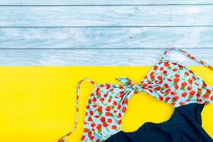 Top view of the swimsuit lying on a blue wooden and yellow background.Summer vacation concept photo