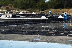 A partial view of a woman putting salt in powder on a white surface.Salt production island of Mauritius photo