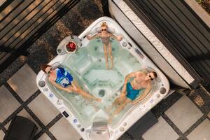 Top view of a family relaxing in an outdoor hot tub in summer photo