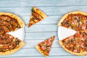 Two different delicious big pizzas on a blue wooden background photo