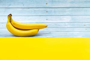Yellow bananas lie on a blue wooden background and a yellow background photo