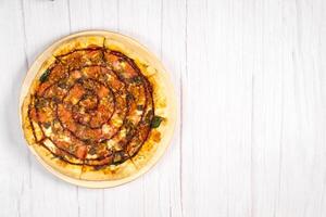 Delicious large pizza with bacon and spinach on a light wooden background photo