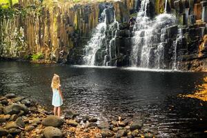 A little girl stands near the Rochester Waterfall on the Island of Mauritius.A waterfall in the jungle of the tropical island of Mauritius photo