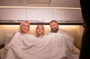 The family is getting ready for bed sitting on the bed in their motorhome photo