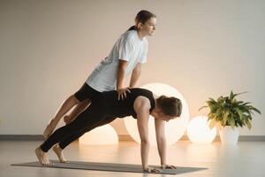 Mom and teenage daughter do gymnastics together in the fitness room. A woman and a girl train in the gym photo