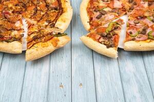 Two different delicious big pizzas on a blue wooden background photo