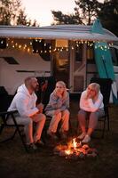 A family cooks sausages on a bonfire near their motorhome in the woods photo